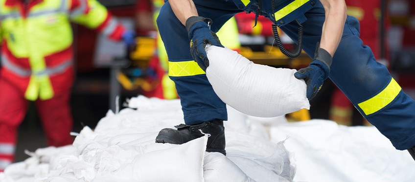 Naturgefahrenversicherung - Feuerwehrmann stapelt Sandsäcke